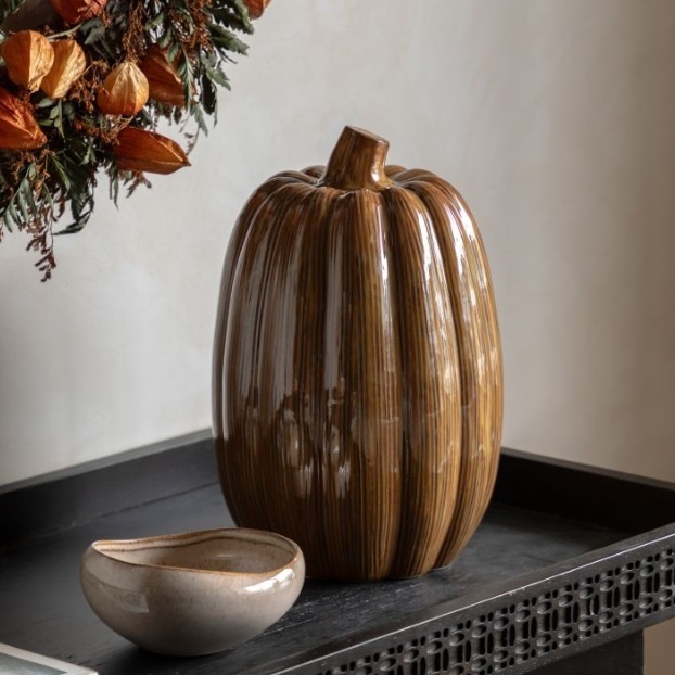 Rust ceramic pumpkin ornament displayed on a console table